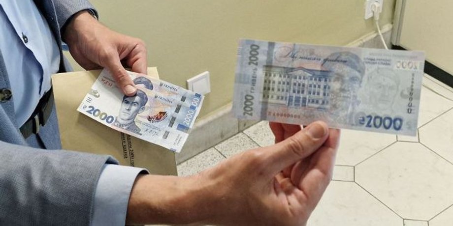 Мужчина держит в руках купюры номиналом две тысячи гривен
