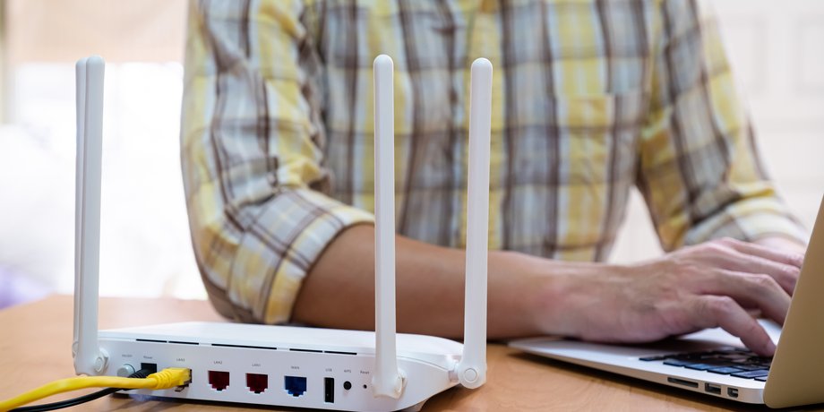 Чоловік працює з ноутбуком перед роутером Wi-Fi