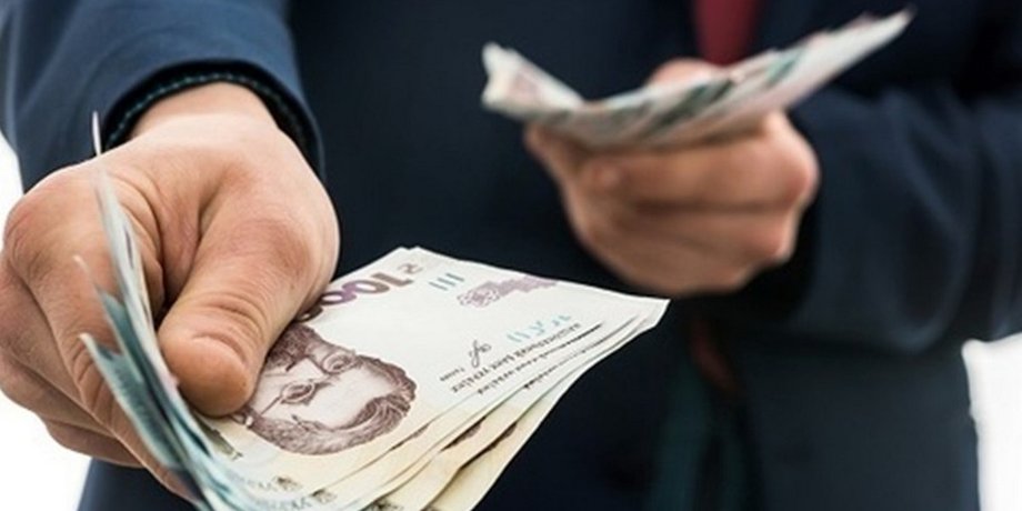 Мужчина держит в обеих руках купюры по тысяче гривен