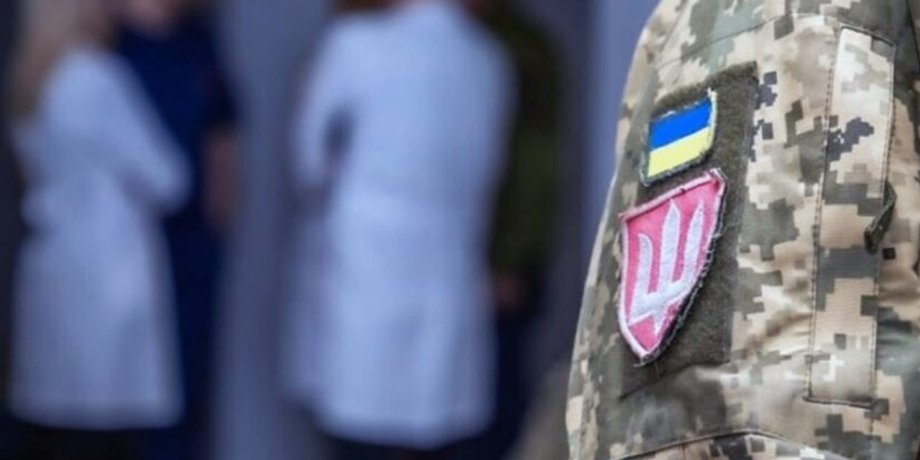 Військовий з нашивкою на формі та кілька лікарів у білих халатах