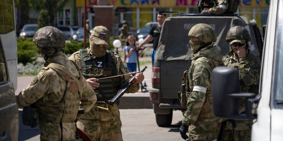 Группа российских военных в городе на машине и с оружием