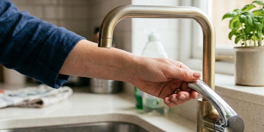 Женщина проверяет, есть ли вода в кране, на фоне проблем с давлением в системе водоснабжения в Киеве