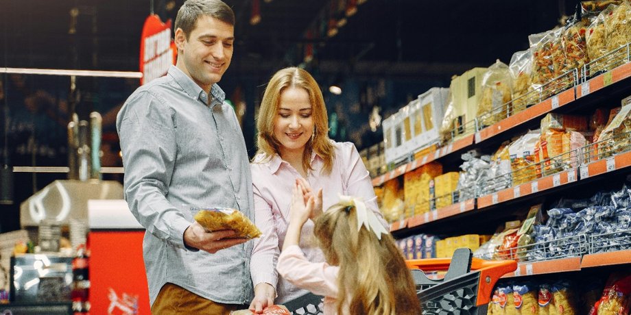 Семья в супермаркете у полок с продуктами