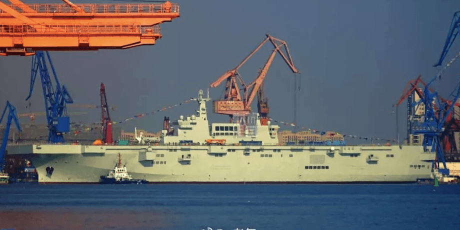 Вертолетоносец Type 075 показан в воде в окружении буксиров