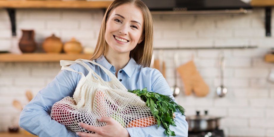 Дівчина тримає в руках авоську з продуктами