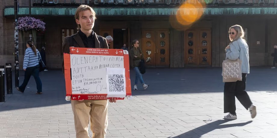 21-річний українець стоїть у центрі Гельсінкі з плакатом про пошук роботи та практики у сфері бухгалтерії