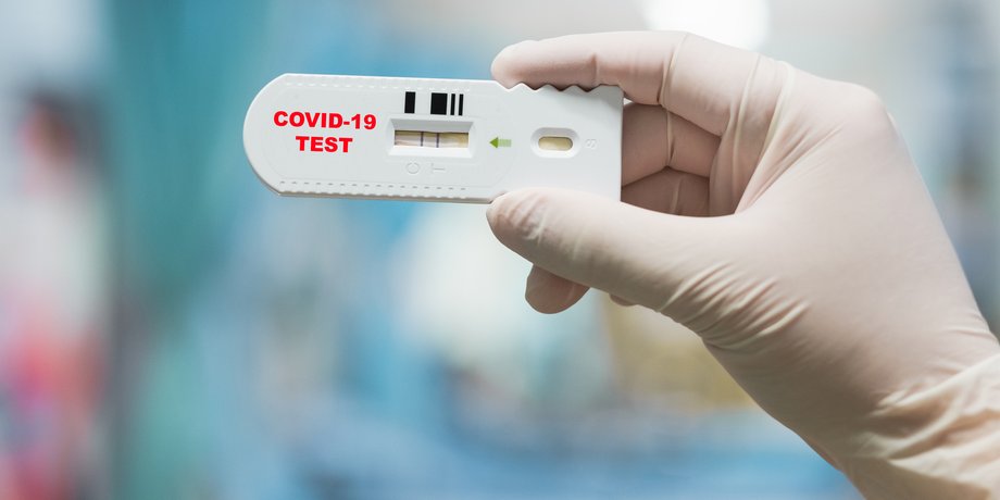 Врач держит тест на COVID-19 с положительным результатом