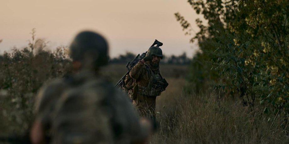 Бійці ЗСУ йдуть зі зброєю у військовій формі лісом