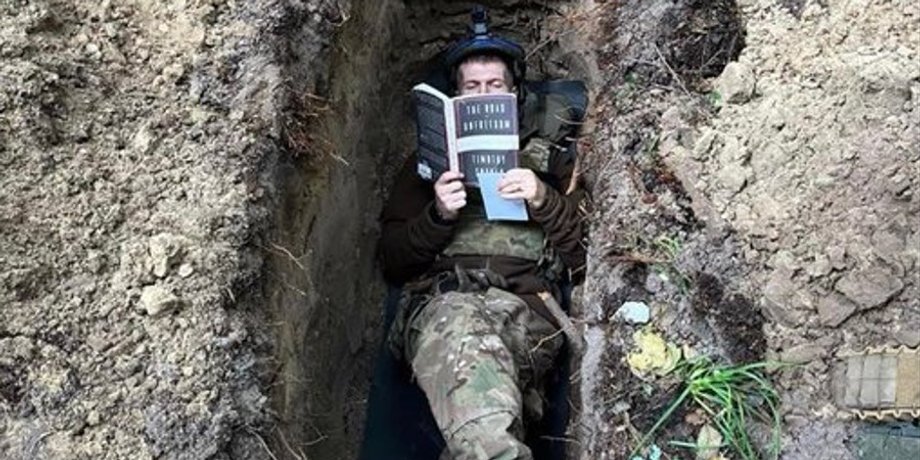 солдат в окопі читає книгу