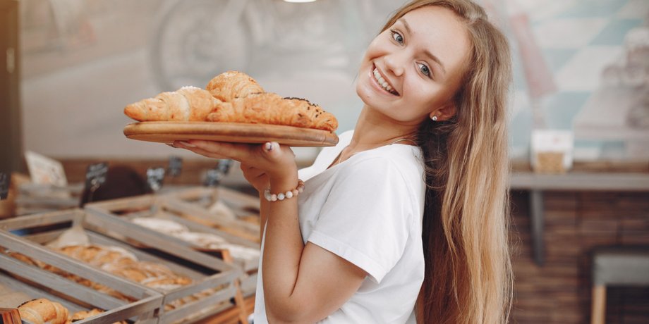 Девушка держит поднос с круассанами