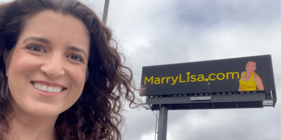 Американка Ліза Каталано посміхається на тлі білборда з написом MarryLisa.com у США