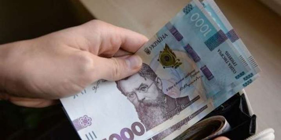 Людина тримає купюри по 1000 гривень