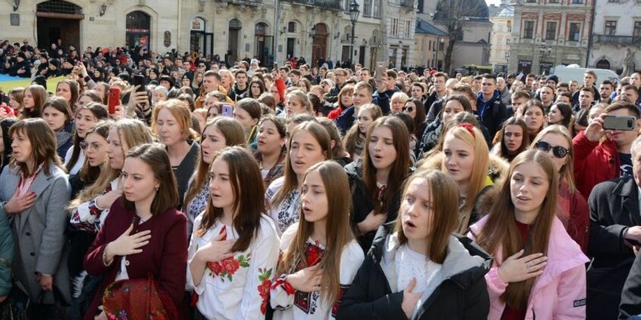 Люди кладут руку на сердце и поют Государственный гимн Украины, который хотят изменить
