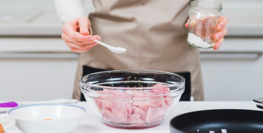 Девушка солит мясо