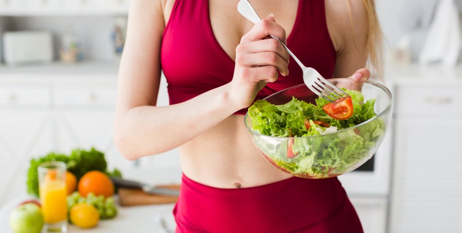 Девушка держит в руках вилку и миску салата