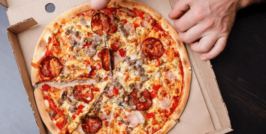 Мужчина режет пиццу