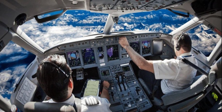 Кабіна пілотів пасажирського літака над хмарами Два пілоти керують пасажирським літаком над хмарами під час польоту