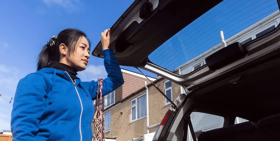 Багажник машини, жінка поруч із машиною, страх став реальністю, зазирнувши в багажник, щур у багажнику, щур у машині,