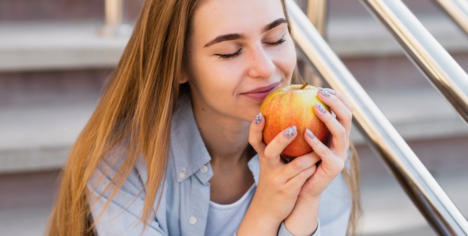 Девушка ест яблоко