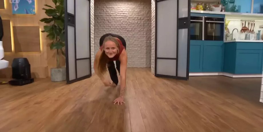 Женщина показывает упражнения квадробики, передвигаясь на четвереньках по полу студии