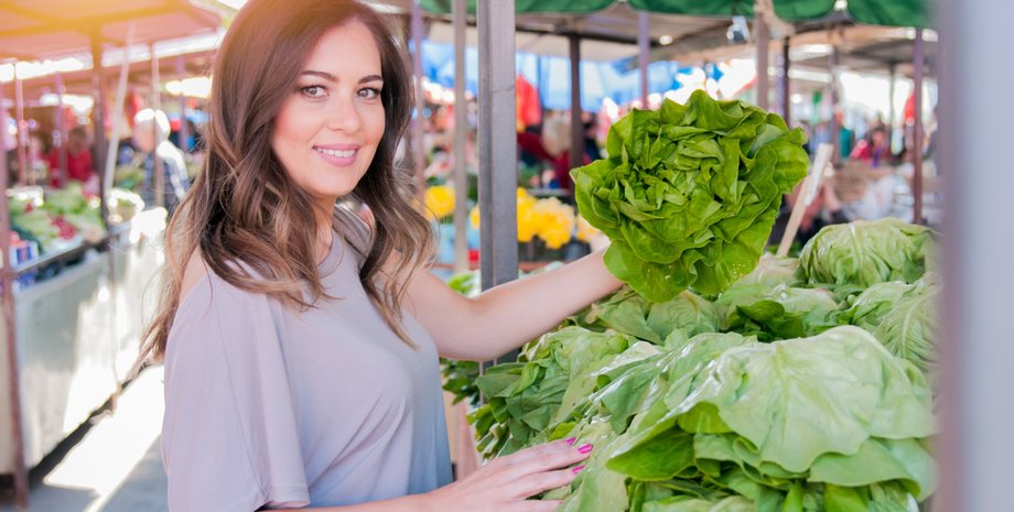 Девушка на рынке выбирает листья салата
