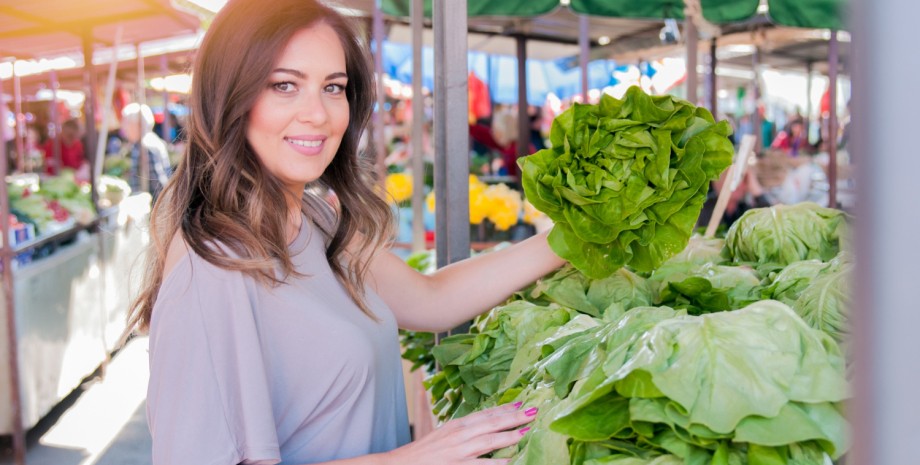 Девушка на рынке выбирает листья салата