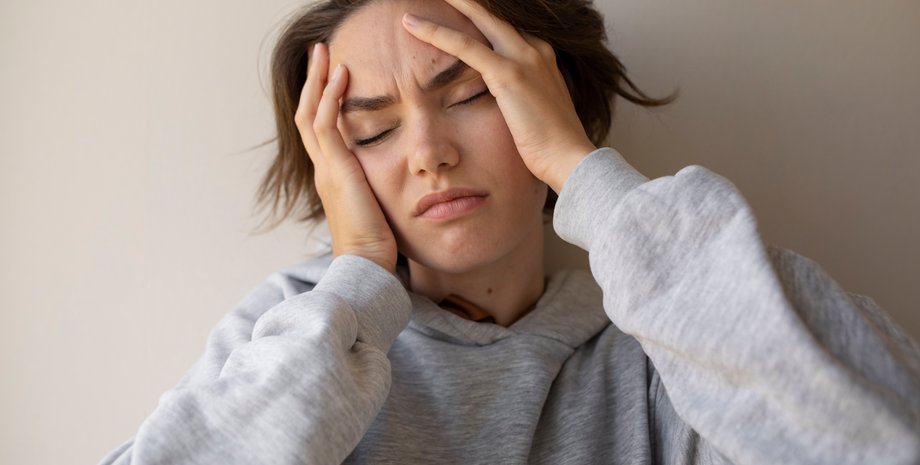 Девушка держит голову руками