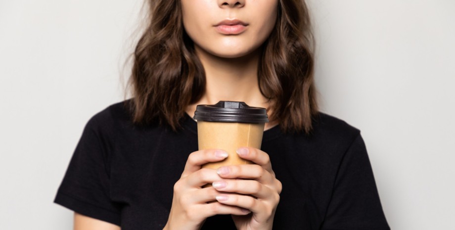 Дівчина п'є каву Дівчина тримає склянку кави