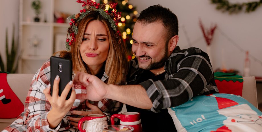 Женщина и мужчина со смартфоном на Новый год