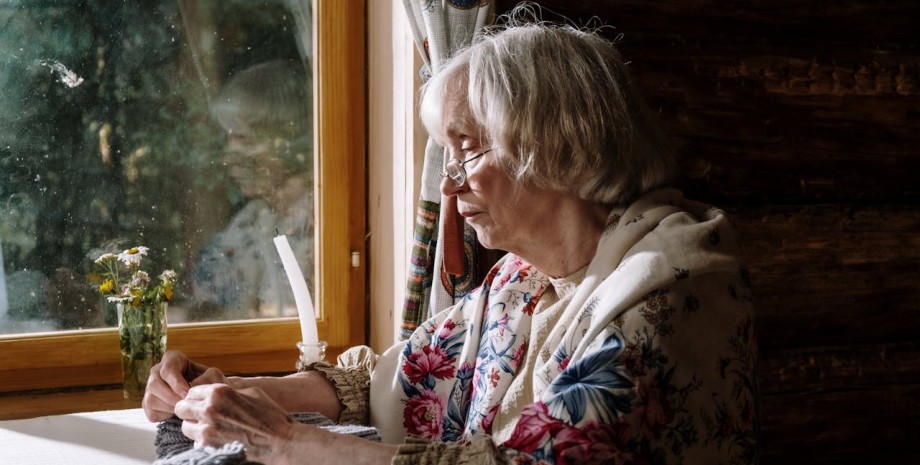 Жінка пенсійного віку біля вікна жінка, пенсіонерка, вікно,