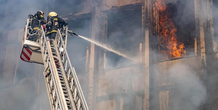 Зображення двох рятувальників, які гасять пожежу в багатоповерхівці
