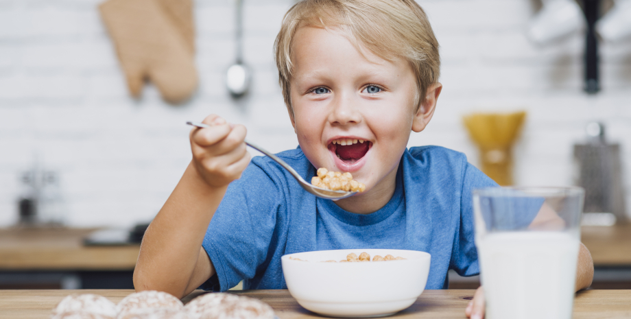 Ребенок за столом ест кашу Ребенок за столом ест кашу