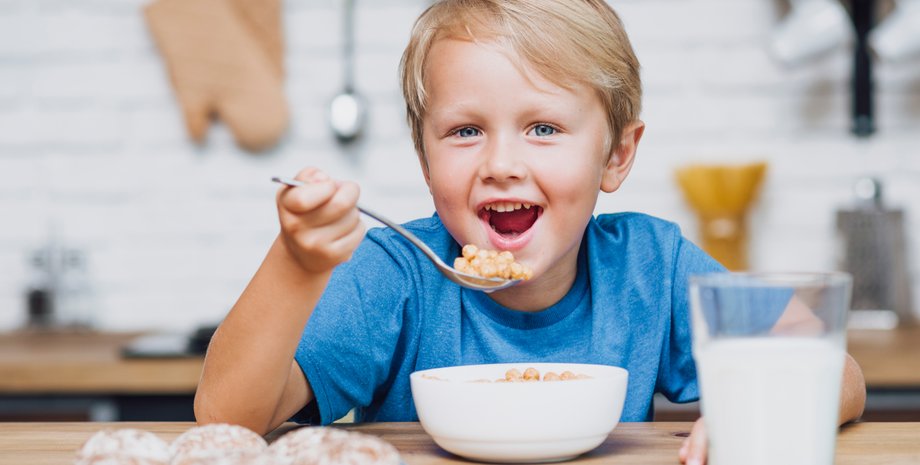 Ребенок за столом ест кашу