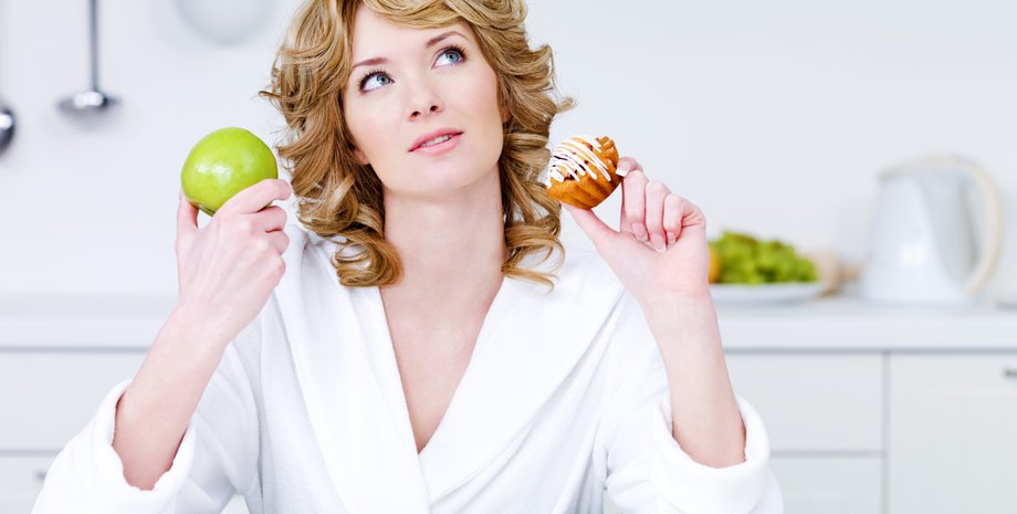 Девушка держит в руке яблоко и пирожное