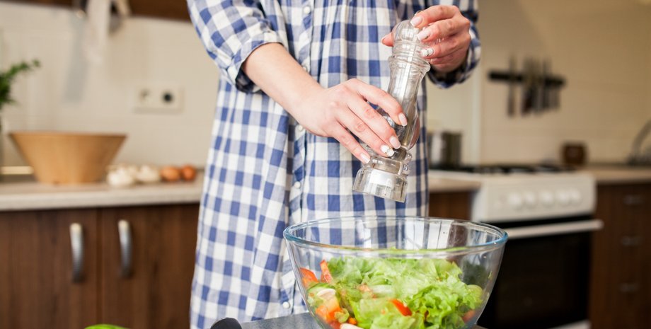 Девушка солит салат