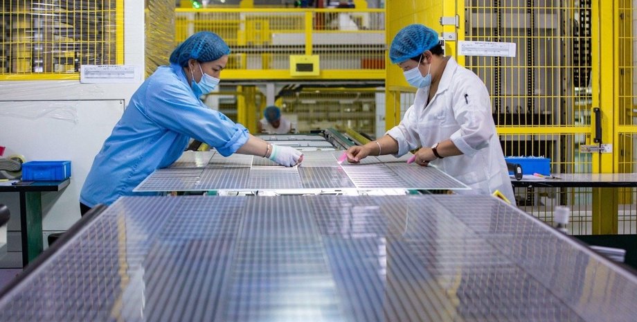 Работники собирают солнечные панели на заводе в Китае