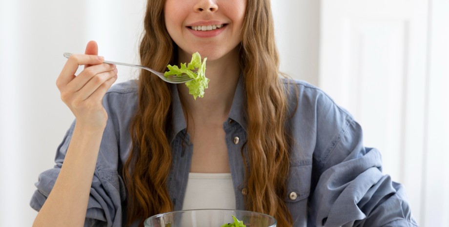 Дівчина їсть салат із зелені