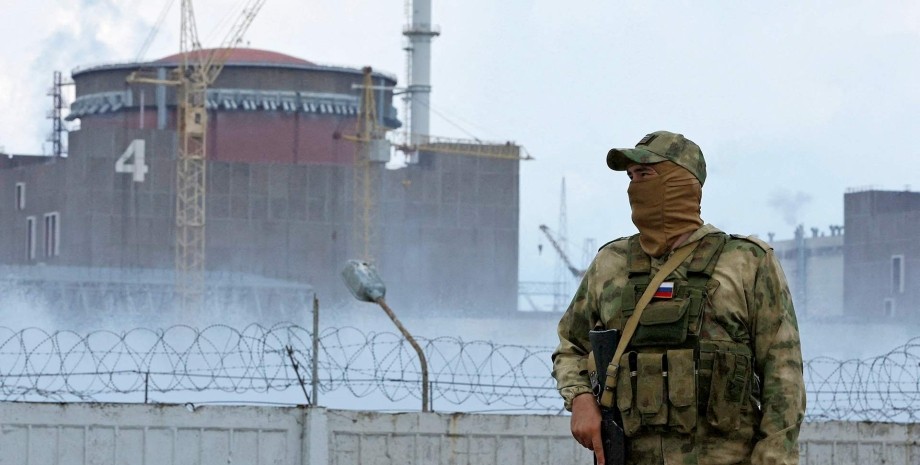 заэс, российский оккупант, солдат рф на фоне заэс, запорожская атомная электростанция, атомная станция в запорожье