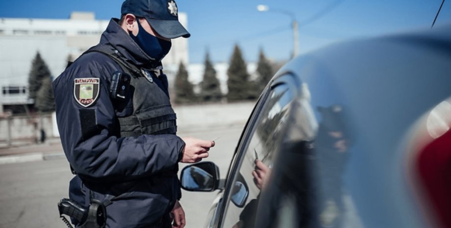 Патрульний перевіряє авто Працівник патрульної поліції під час зупинки авто для перевірки