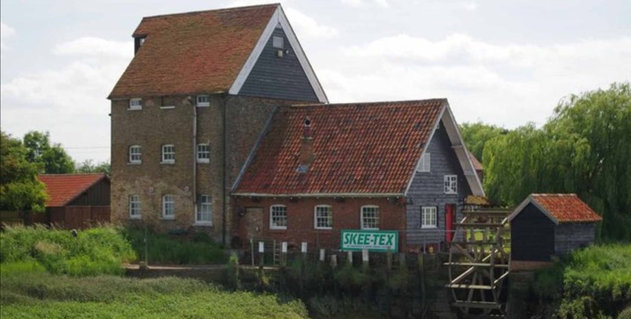 Старая приливная мельница в Сассексе, Великобритания, здание с красной крышей у воды