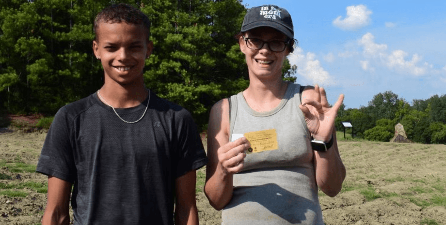Мать и сын улыбаются, держа в руках найденный в парке драгоценный камень