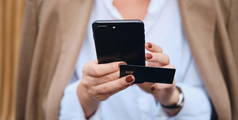 Женщина держит смартфон и банковскую карту