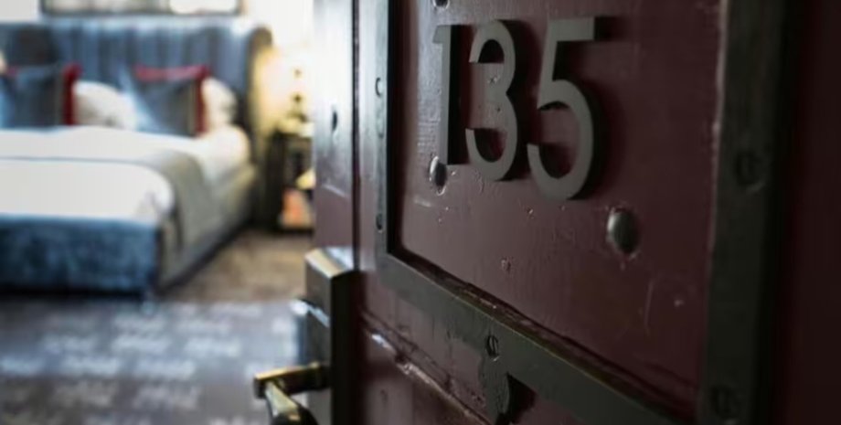 Двері готельного номера перед виявленням дивних слідів на вікні Відчинені двері в номер готелю з видимим номером кімнати перед знахідкою відбитків на запітнілому вікні
