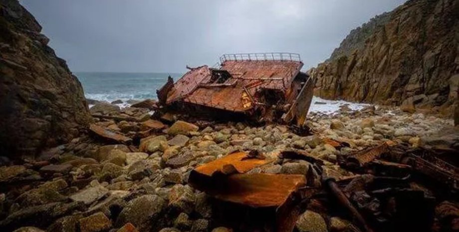 Ржавые обломки корабля, выброшенного на каменистый берег в бухте Лендс-Энд, Англия