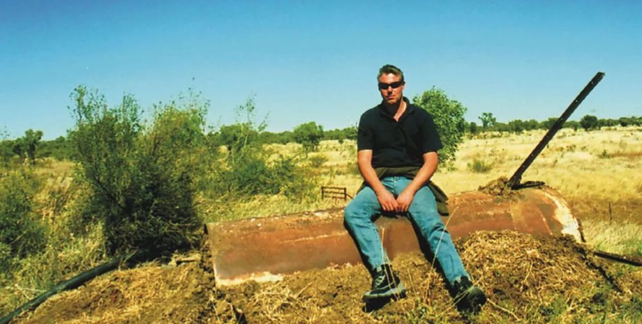 Рікі Мегі сидить на покинутій конструкції в пустельній місцевості Австралії