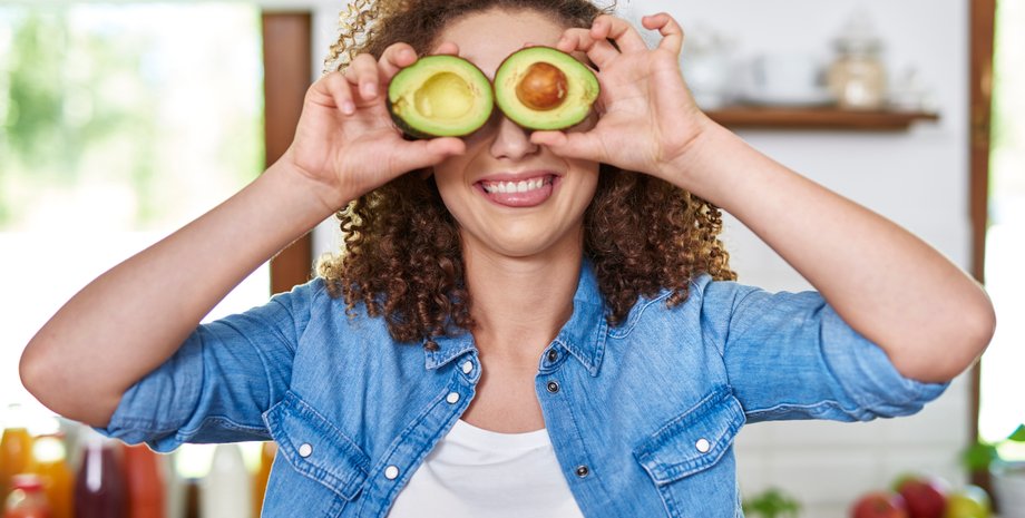 Девушка держит в руках половинки авокадо