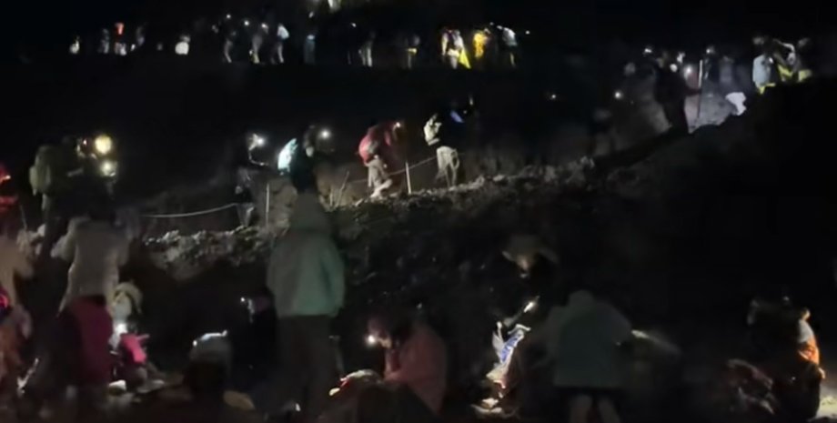 Толпы туристов с фонариками поднимаются по темному склону горы Фудзи перед рассветом