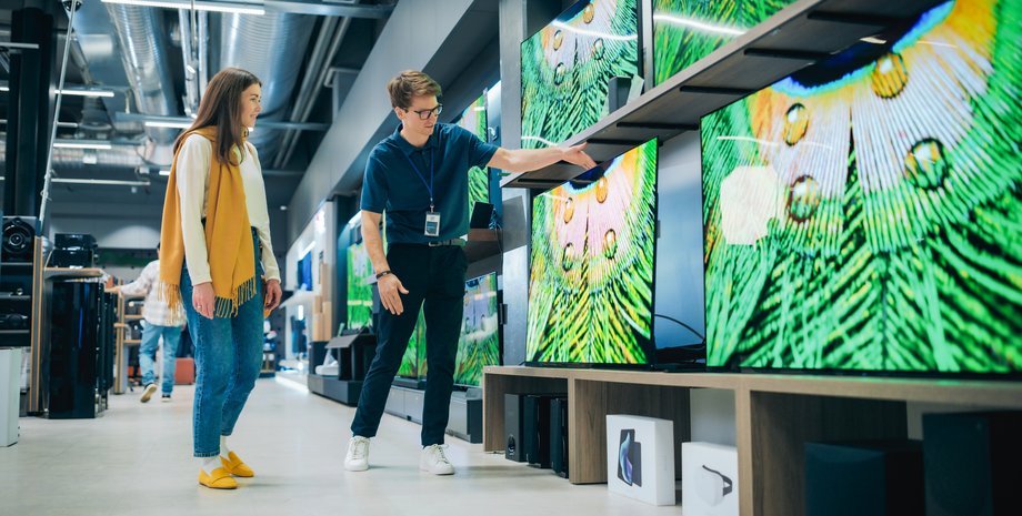 Девушка с продавцом выбирает телевизор в магазине