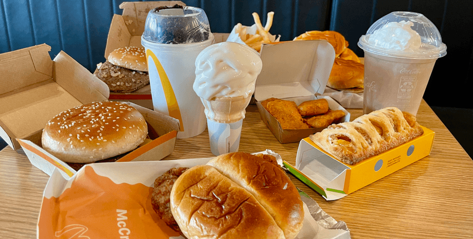 Разнообразные блюда McDonald's на столе: бургеры, картофель фри, наггетсы, мороженое и пирожок
