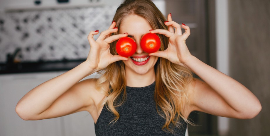 Девушка держит два помидора у лица